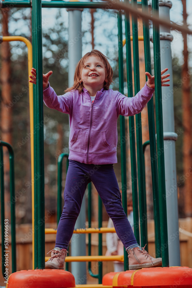 Fototapeta premium A little girl playing in the park. The concept of family socializing in the park. A girl swings on a swing, plays creative games