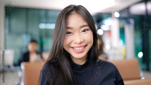 Attractive Asian female traveller smile looking at camera while waiting for her flight at airport terminal. travel idea concept