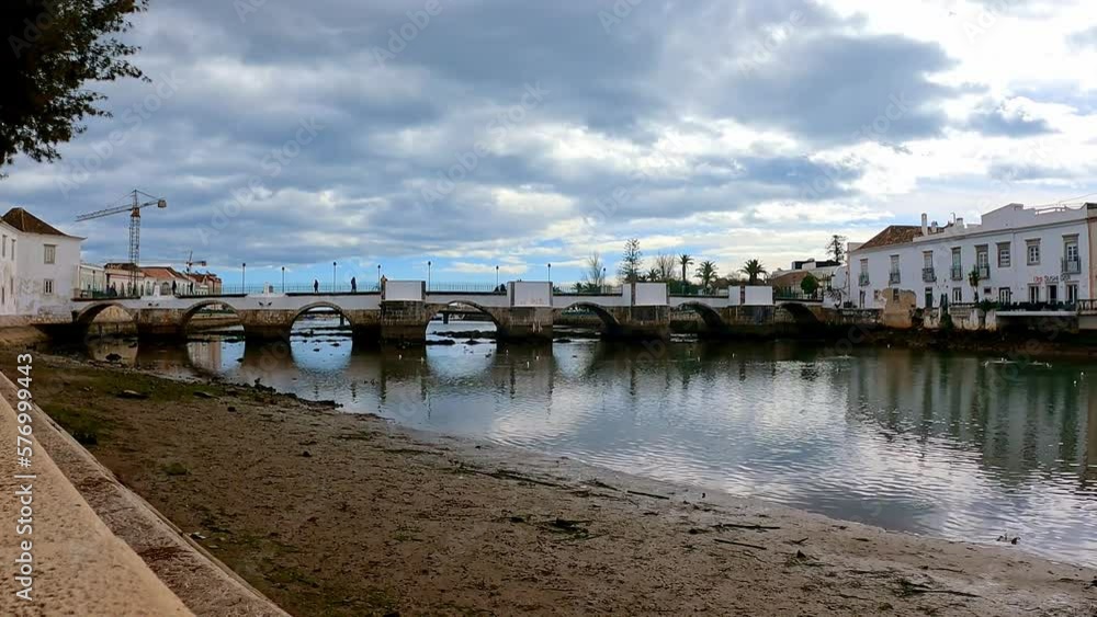 Early morning at Ponte Romana Bridge, the Galao River at low tide, showery spring day in this romantic town Tavira on the Algarve Portugal Early morning at Ponte Romana Bridge, the Galao River at low tide, showery spring day in this romantic town Tavira on the Algarve Portugal