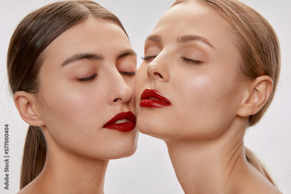 Two sensual beautiful young women with nude makeup and red lipstick posing with closed eyes. Concept of love, emotions, beauty, vision, health and fashion Two sensual beautiful young women with nude makeup and red lipstick posing with closed eyes. Concept of love, emotions, beauty, vision, health and fashion