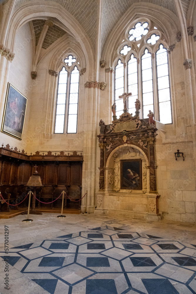 Pequeña sala de la Catedral de Burgos con la luz entrando por las vidrieras de la pared, con cuadros colgados en las paredes.