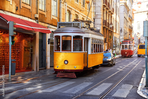 Lisbon, Portugal. Vintage yellow retro tram on narrow bystreet tramline in Alfama district of old town. Popular touristic attraction Lisboa city