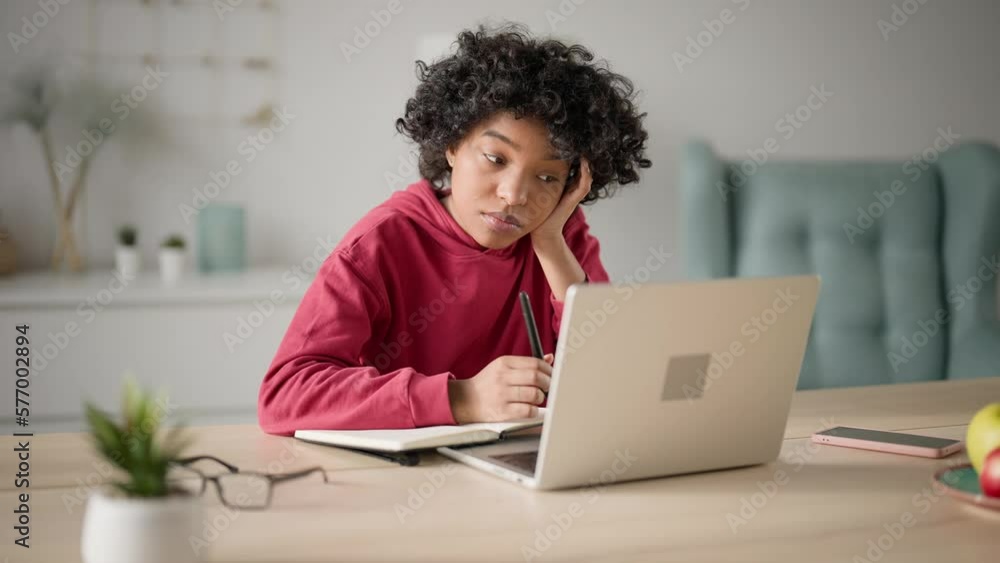 Young woman, student studying at online lesson using laptop making notes in copybook. Girl at online video conferences communicates and answers questions sitting home desk. Concept distance learning. Young woman, student studying at online lesson using laptop making notes in copybook. Girl at online video conferences communicates and answers questions sitting home desk. Concept distance learning.