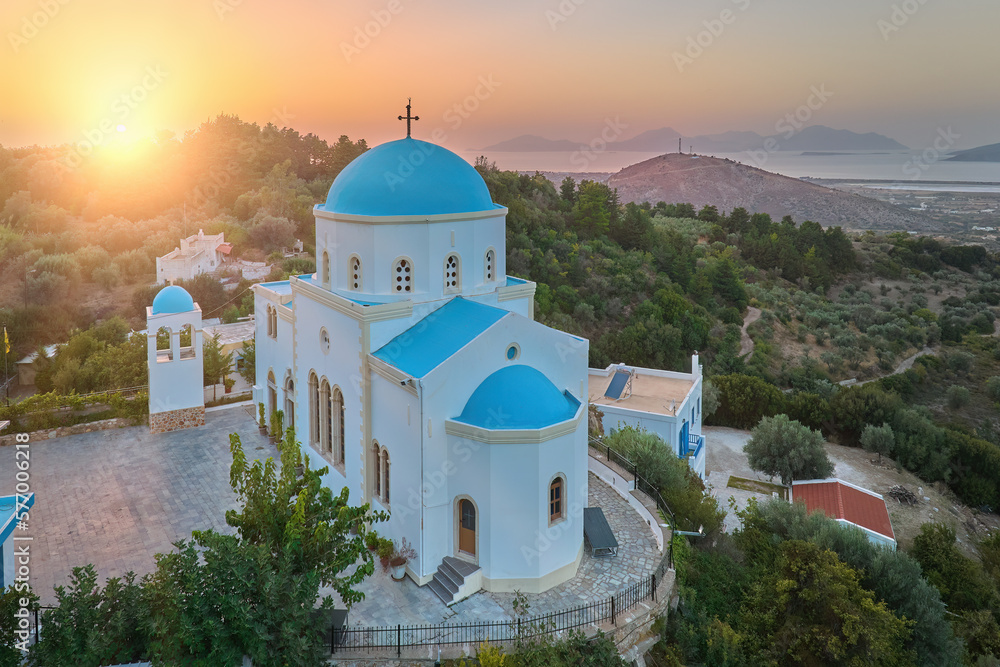 Aerial view of the Lagoudi Zia Church on  Greek island of Kos. Typical blue roofs monastery near Zia town against Sunset. Vibrant colors, no people, calm atmosphere.