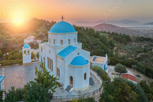 Aerial view of the Lagoudi Zia Church on Greek island of Kos. Typical blue roofs monastery near Zia town against Sunset. Vibrant colors, no people, calm atmosphere.