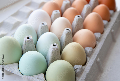 Lot of different color chicken eggs arranged by color on paper egg box. All sorts of colors: blue, green, white, beige, brown. From natural organic farm. Minimal above view. photo