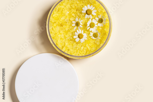 Bath salt sea with herbal extract of chamomile, natural sea salt crystals in round jar, decorated natural chamomile flowers. Aromatherapy and herbal medicine, body care cosmetics, copyspace photo