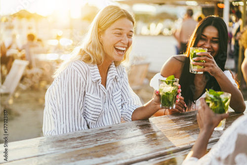 Obraz na płótnie Happy girls having fun drinking cocktails at bar on the beach - Summer lifestyle