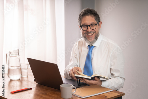 Happy mature businessman sitting at desk and looking at camera with a smile
