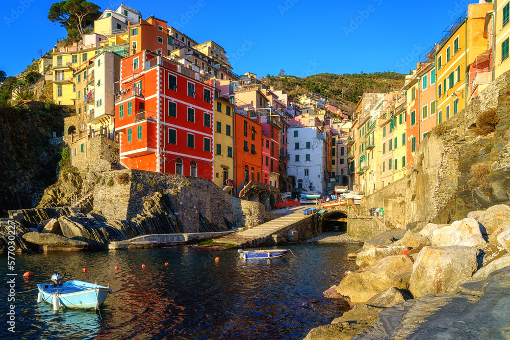 Stunning view of Riomaggiore village in Cinque Terre National Park, beautiful cityscape with colorful houses and green terraces on cliffs over a sea, Liguria region of Italy. Outdoor travel background