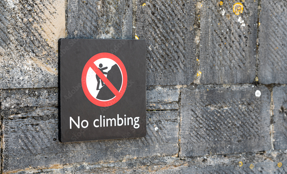 No Climbing sign fixed to a brick stone wall in the UK England No Climbing sign fixed to a brick stone wall in the UK England