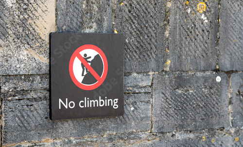 No Climbing sign fixed to a brick stone wall in the UK England