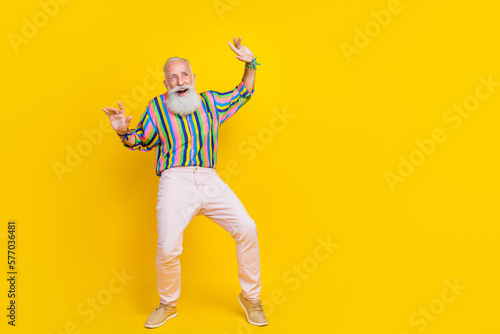 Full length photo of cheerful charming man wear colorful shirt daning looking empty space isolated yellow color background