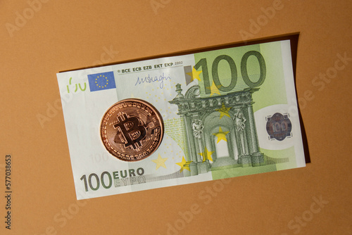 Bitcoin gold coin on bills of 100 euros eu currency. Bitcoin mining trading concept. BTC golden money. Worldwide virtual internet Cryptocurrency or crypto digital payment system. Digital coin money photo