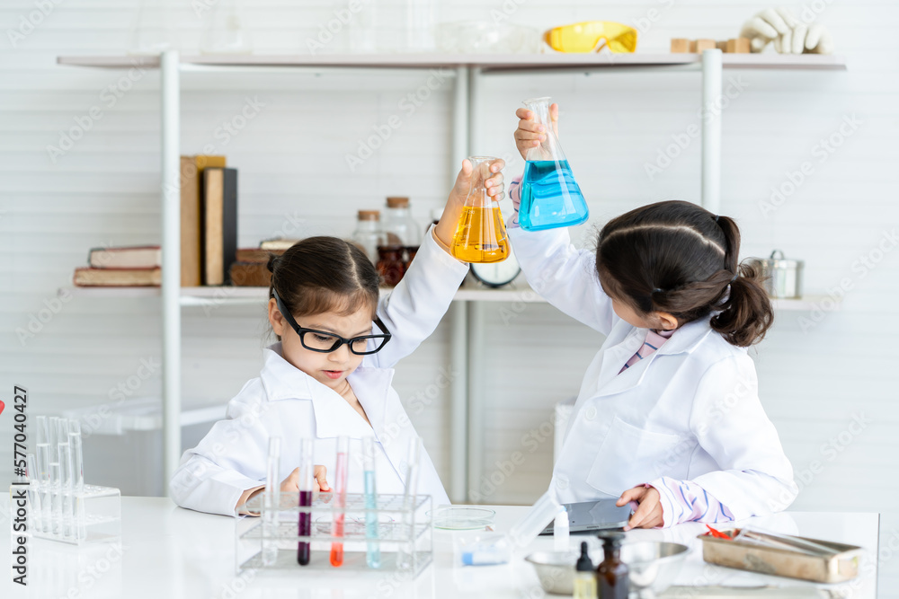 Two Arab girls are playing with A blue-yellow solution in a test tube for a friend to examine before recording, childhood naughty toy in a school lab. Concept Education, Science Experiment, Chemistry Two Arab girls are playing with A blue-yellow solution in a test tube for a friend to examine before recording, childhood naughty toy in a school lab. Concept Education, Science Experiment, Chemistry