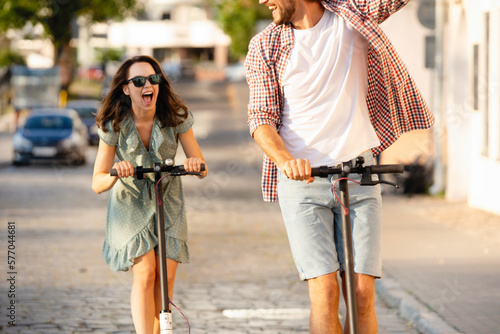 Happy young couple in love on vacation having fun, driving electric scooter through the city. Eco transport