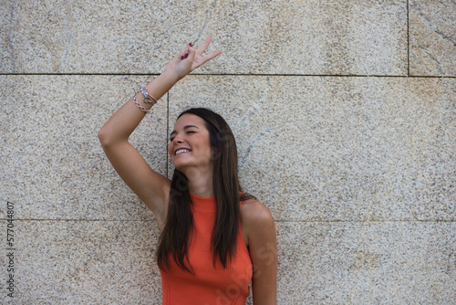 beautiful young woman raises her arms with clenched fists celebrating victory and achievements on gray background.