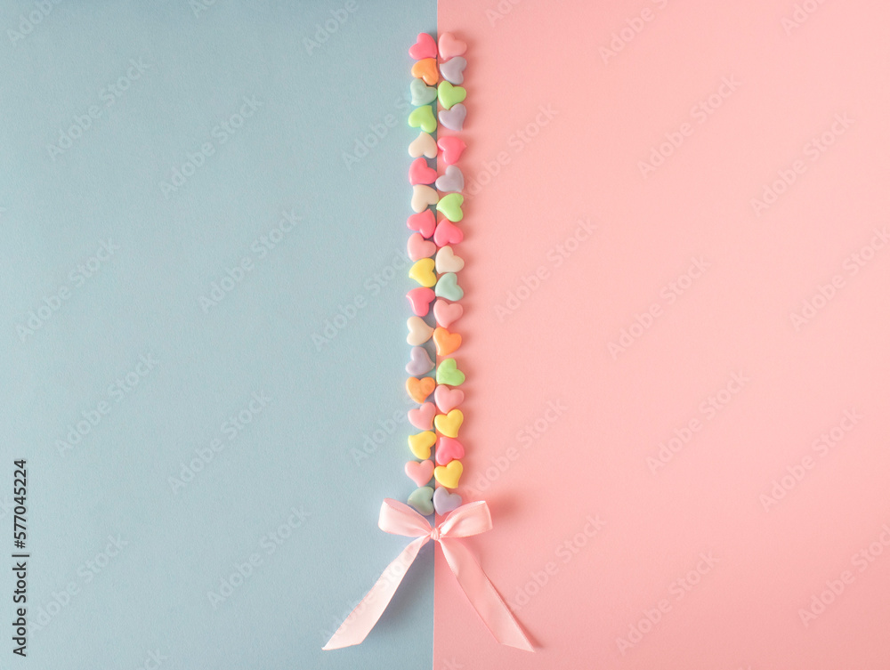 Pink, blue, yellow, green, purple, orange white hearts with pink bow on pink and blue background. Unique, lovely concept. Flat lay. Top view. Pink, blue, yellow, green, purple, orange white hearts with pink bow on pink and blue background. Unique, lovely concept. Flat lay. Top view.