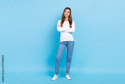 Full length photo of funny dreamy lady dressed white shirt arms folded looking emtpy space isolated blue color background