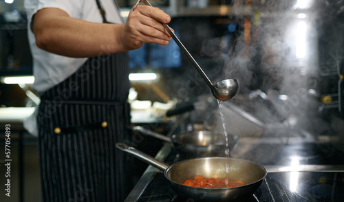 Chef adding white wine to frying pan with tomato sauce for pasta