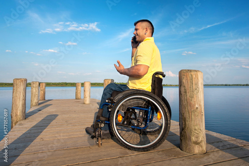 Rollstuhlfahrer mit Handy am See