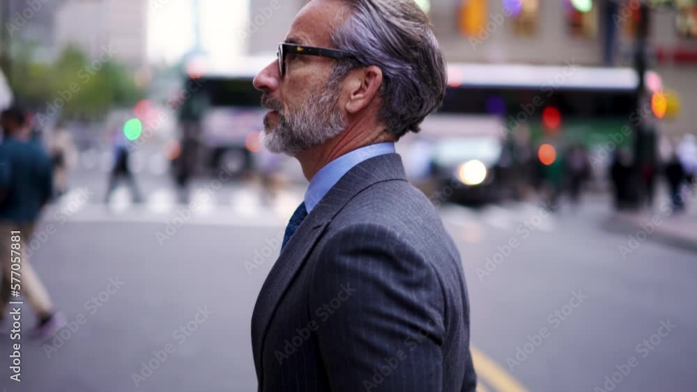 Successful businessman in suit with cellphone crosses city road t in financial district. Confident entrepreneur in stylish eye glasses walking forward outdoors in downtown. Slow motion Successful businessman in suit with cellphone crosses city road t in financial district. Confident entrepreneur in stylish eye glasses walking forward outdoors in downtown. Slow motion