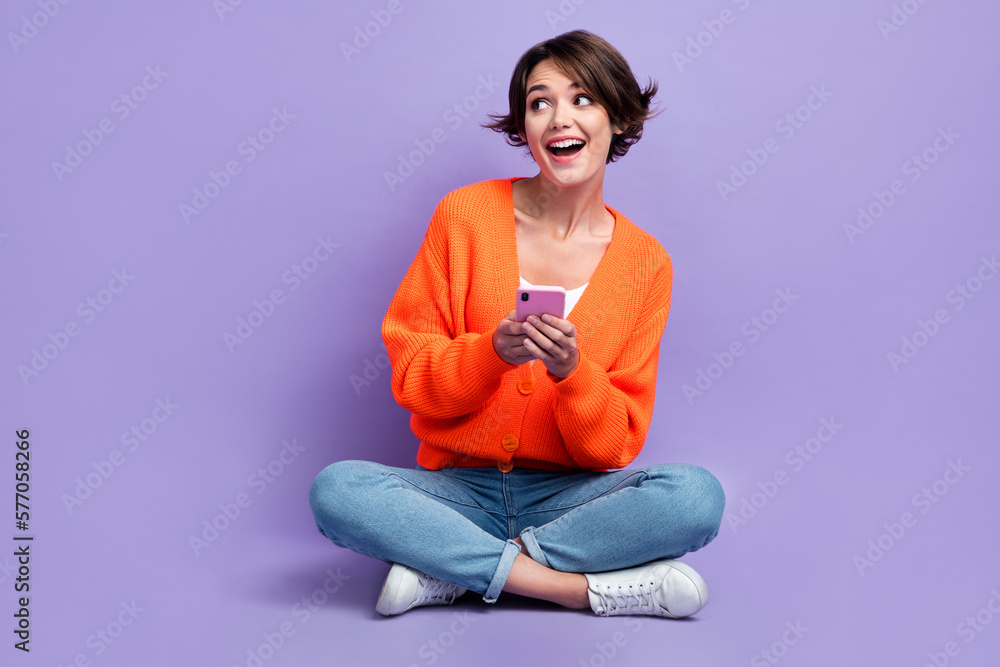 Full body photo cadre of surprised woman wear knitted orange cardigan look empty space online black friday offer isolated on purple color background Full body photo cadre of surprised woman wear knitted orange cardigan look empty space online black friday offer isolated on purple color background