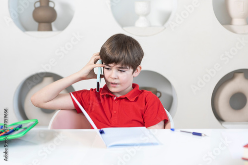 Cute school boy sits at the desk and learns his lessons