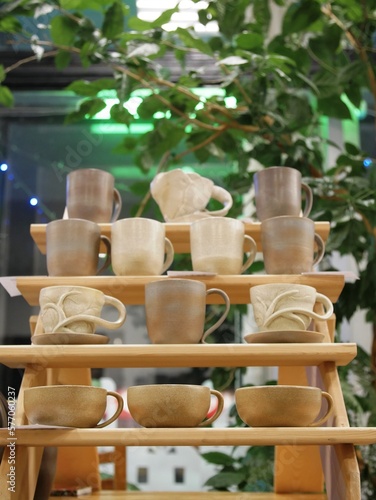 Craft ceramic beige mug handmade cup on wooden shelf, copy space
