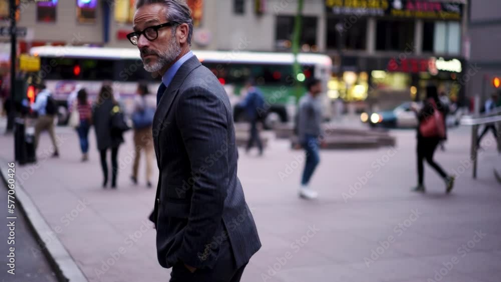 Successful businessman in suit with cellphone crosses city road t in financial district. Confident entrepreneur in stylish eye glasses walking forward outdoors in downtown. Slow motion Successful businessman in suit with cellphone crosses city road t in financial district. Confident entrepreneur in stylish eye glasses walking forward outdoors in downtown. Slow motion