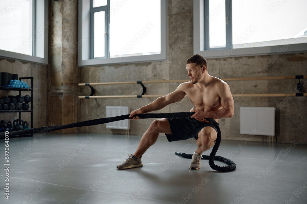 Obraz premium A strong man pulling training sports rope front view