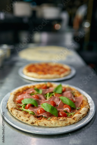 Stages of pizza preparation with selective focus on freshly baked Italian dish