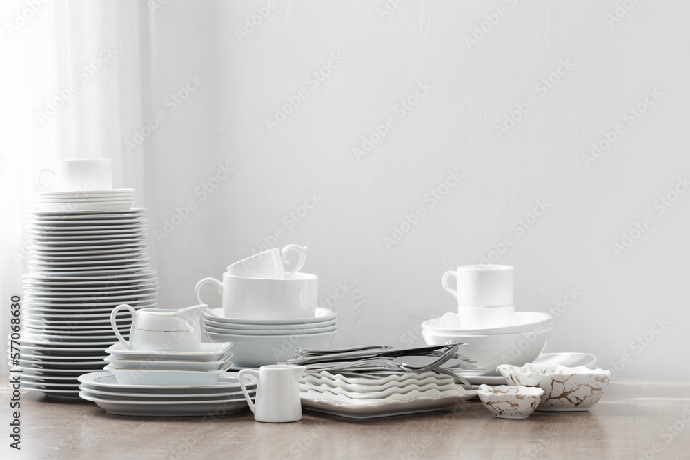 various cutlery on a wooden table against a white wall various cutlery on a wooden table against a white wall