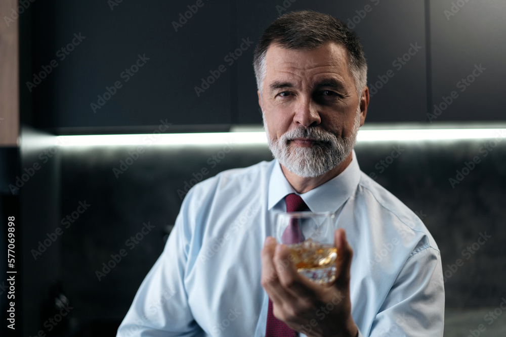 Confident rich mature wealthy businessman chilling relaxing drinking enjoying whiskey in the kitchen after work. Confident rich mature wealthy businessman chilling relaxing drinking enjoying whiskey in the kitchen after work.