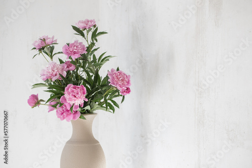 pink peony in ceramic vase on background old wall
