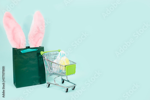 Easter shopping concept. Green paper bag and colorful eggs in a grocery basket. Place for text, advertising. High quality photo