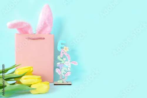 Postcard for Easter with a place for text. On a blue background, rabbit ears in a gift bag tulips and the inscription. High quality photo