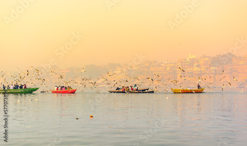 Tourists feeding the migratory birds at the popular boat tour on the sacred Ganges river in Varanasi, Uttar Pradesh, India photo