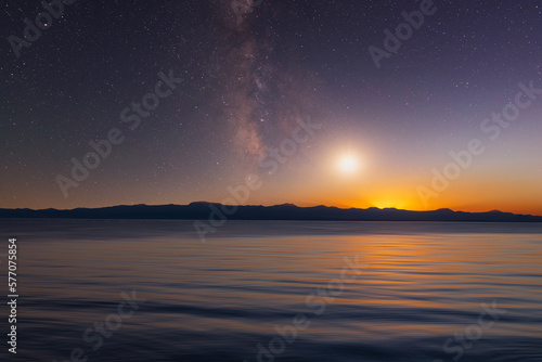 Milky Way galaxy and moon over the mountains and lake. Beautiful night landscape.