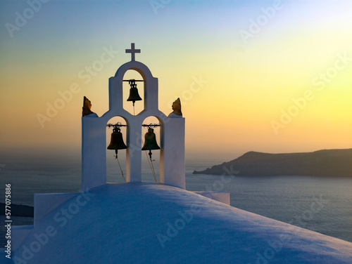Sunset over the Bell Tower of a church in town of Oia on the clifftop above the volcanic caldera on the Greek volcanic island of Santorini (Thira) in the southern Aegean Sea.. photo