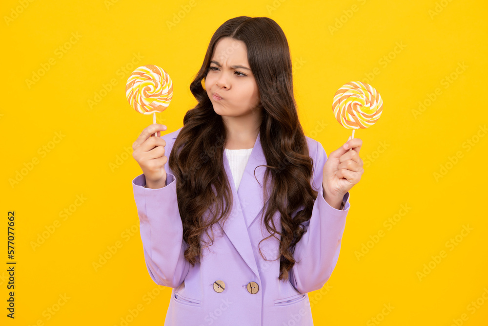 Thinking teenager girl, thoughtful emotion. Teenager girl eating sugar lollypop. Candy and sweets for kids. Child eat lollipop popsicle over yellow isolated background. Yummy caramel, candy shop. Thinking teenager girl, thoughtful emotion. Teenager girl eating sugar lollypop. Candy and sweets for kids. Child eat lollipop popsicle over yellow isolated background. Yummy caramel, candy shop.