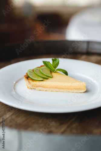 Lemon tart garnished with mint and lemon on a large white plate
