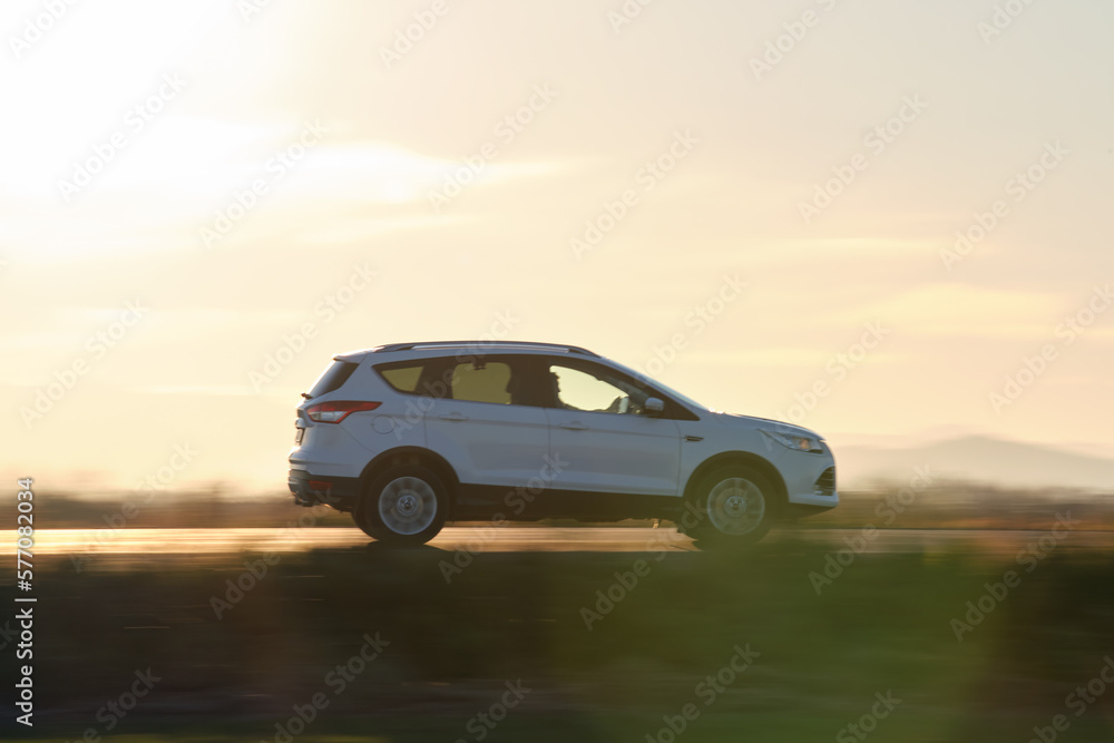 SUV car driving fast on intercity road at sunset. Highway traffic in evening SUV car driving fast on intercity road at sunset. Highway traffic in evening