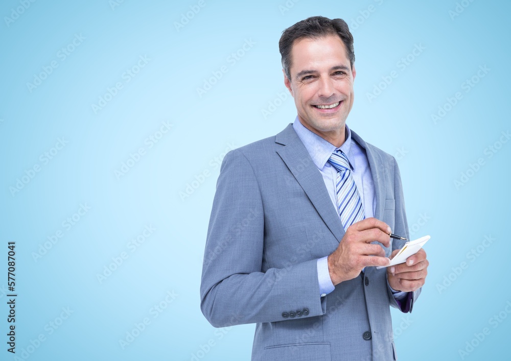 Portrait of caucasian businessman smiling an taking notes against copy space on blue background Portrait of caucasian businessman smiling an taking notes against copy space on blue background
