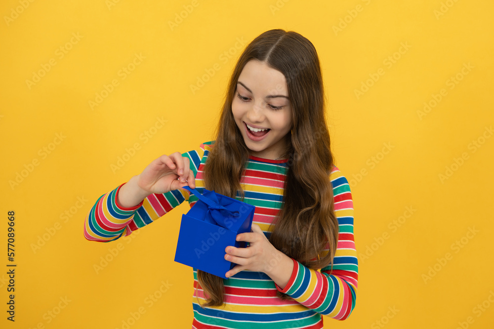 Teenager child holding gift box on yellow isolated background. Gift for kids birthday. Christmas or New Year present box. Teenager child holding gift box on yellow isolated background. Gift for kids birthday. Christmas or New Year present box.