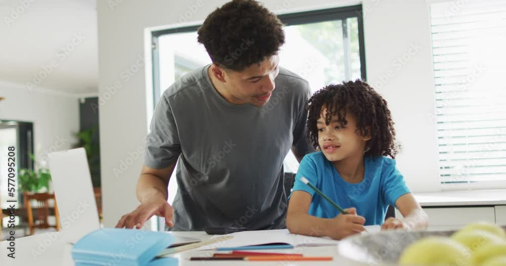 Happy biracial man and his son doing homework together Happy biracial man and his son doing homework together