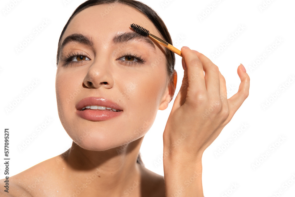brunette woman styling eyebrows with brush and gel isolated on white.