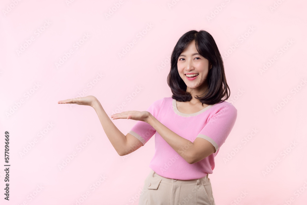 Portrait young beautiful asian woman happy smile pointing finger and hand to showing on copy space isolated on pink background. Attractive female person gesture attention to this promotion. Portrait young beautiful asian woman happy smile pointing finger and hand to showing on copy space isolated on pink background. Attractive female person gesture attention to this promotion.