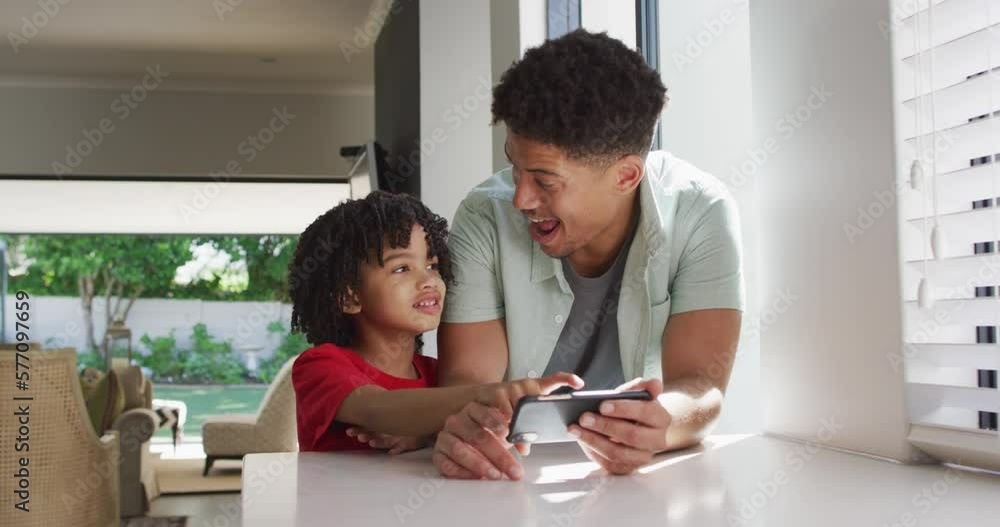 Happy biracial man and his son using smartphone together Happy biracial man and his son using smartphone together