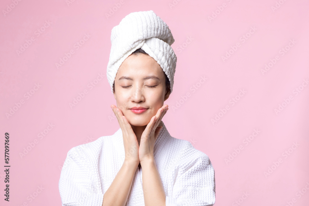 Beautiful young asian woman happy with clean face skin in towel and bathrobe, spa suit on pink background. Skincare, treatment, wellness therapy, facial care, beauty female health, cosmetology concept Beautiful young asian woman happy with clean face skin in towel and bathrobe, spa suit on pink background. Skincare, treatment, wellness therapy, facial care, beauty female health, cosmetology concept